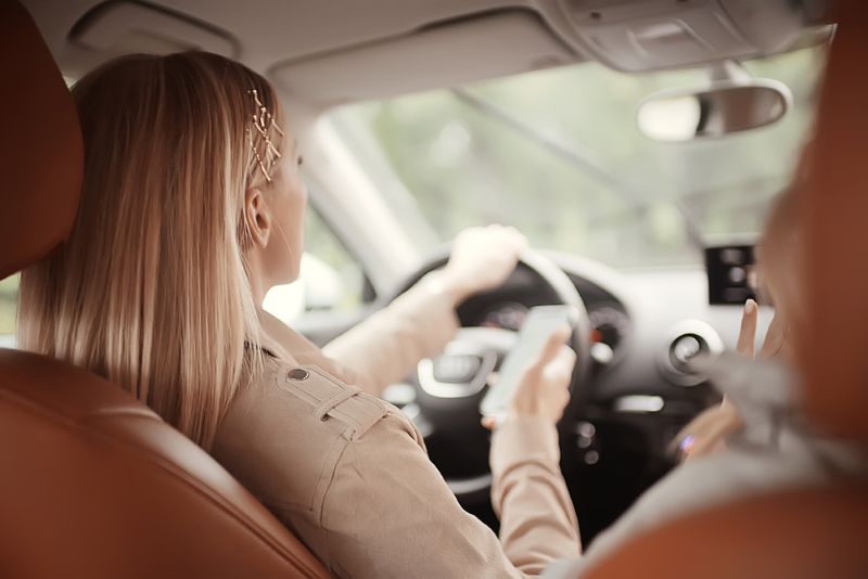 woman on the phone driving with her friend