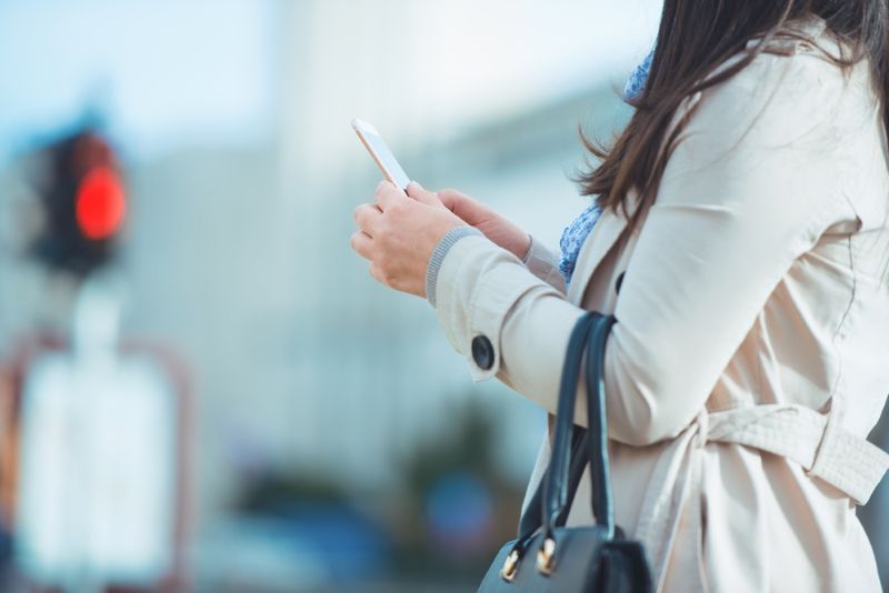 woman looking at her phone as she crosses the street
