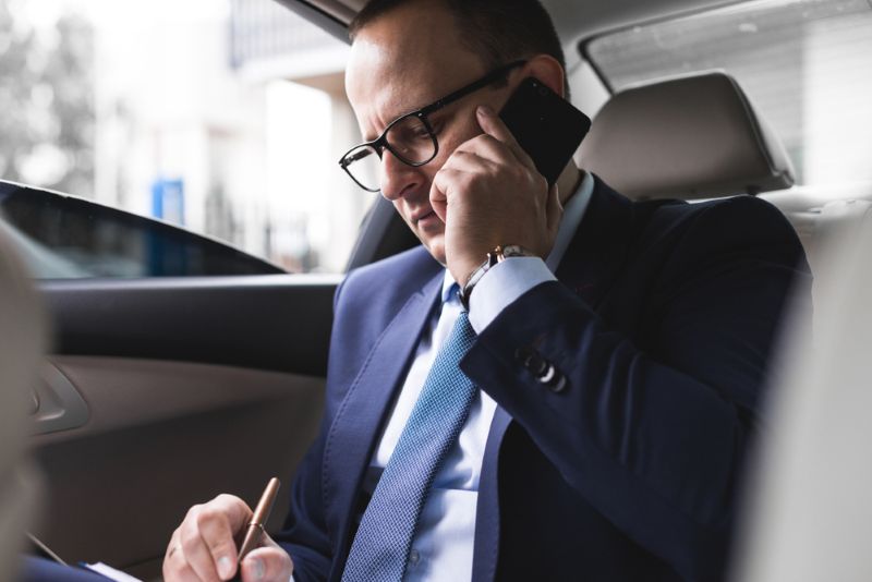 businessman talking on phone in the backseat of a car