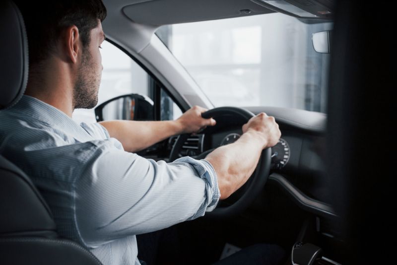 man sitting in driver's seat with both hands on the steering wheel