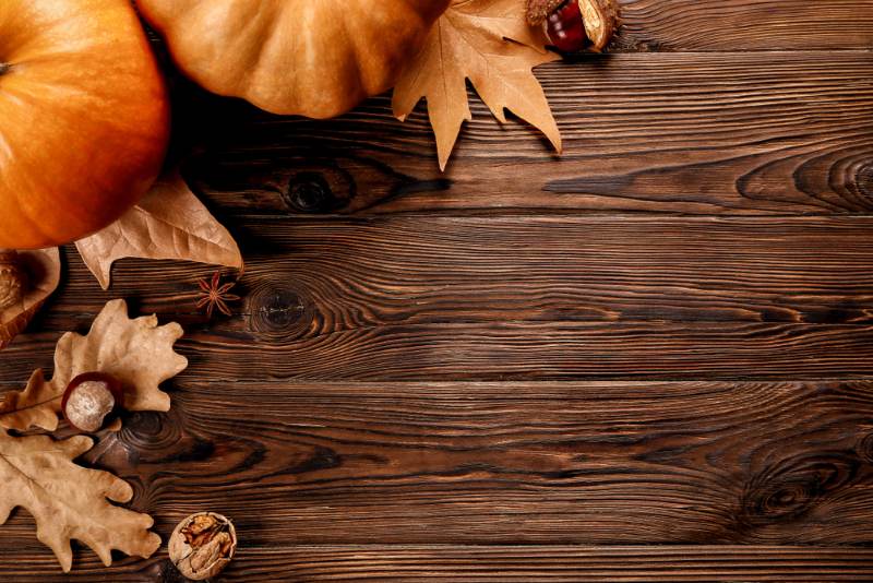 wooden table in autumn with leaves and pumpkins