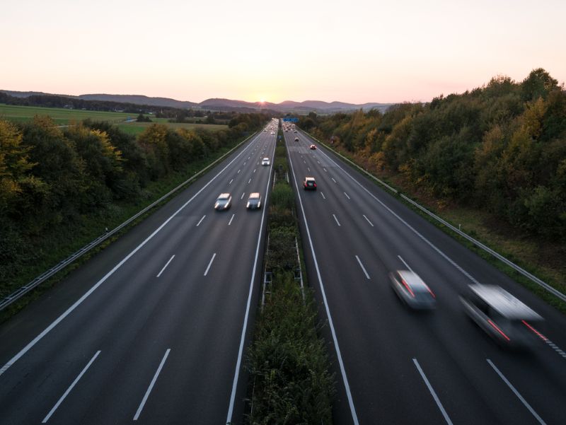 highway with cars travelling in both directions with mountains in background