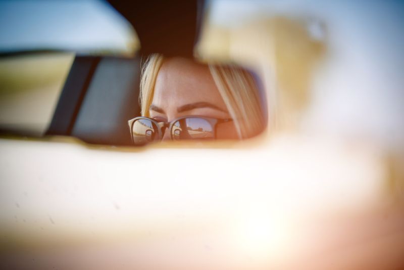 closeup of a woman's eyes in the center mirror of her car