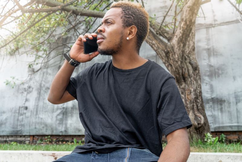 young man sitting outside on a phone call