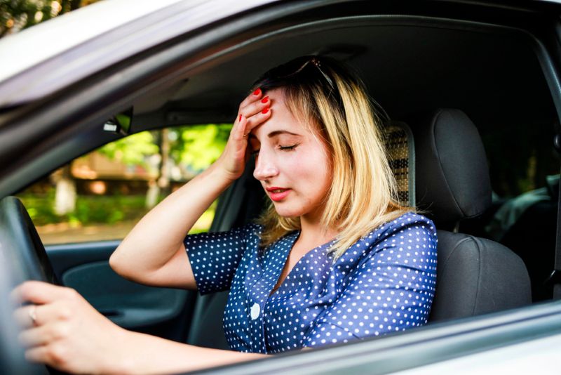 Stressed woman with a hand on her head while driving