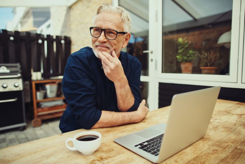 Older man sitting outside of his house working