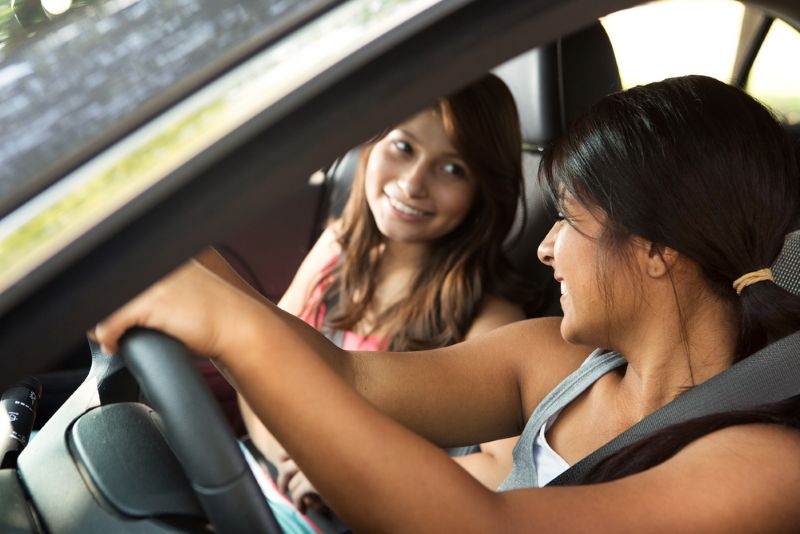 Two young friends laughing while driving