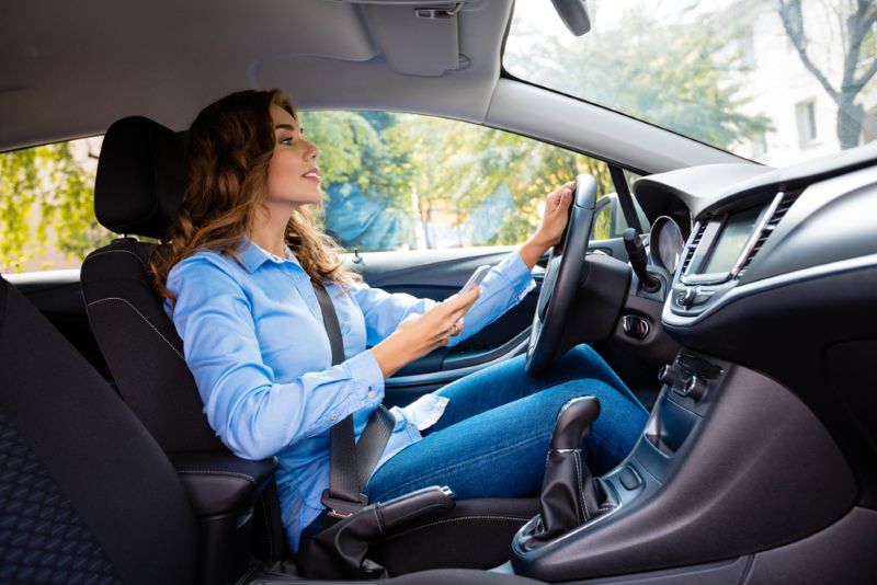 Woman driving with one hand on the wheel during the day